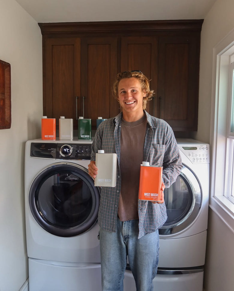 Matt, founder of Mozi Wash, holding detergent tins in a laundry room