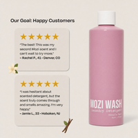 A pink bottle of Mozi Wash Laundry Detergent with a white cap, shown next to two customer review cards on a light beige background. The product label reads 'MOZI WASH' and 'Vanilla Mist'.